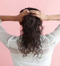 Create a center part, then lean your head back and gently pull hair back at the nape of the neck to create a low ponytail. According to Brill, leaning your hair back to gather the hair helps to create volume behind the ears and above the ponytail. While hair is gathered back, shake your head to allow some front pieces to naturally fall out. Secure hair with an elastic. LowPony_044_R