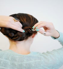 Tuck the remaining hair from the right side over the knot, and the hair from the left underneath. Both strands should be integrated into the initial knot. Then, use the Spin Pin to secure. Continue adding in pins until hair is held firmly in place. braided-hairstyle-8