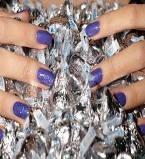 If you've avoided glitter polishes because they're a bear to remove — and they can be! — here's a solution. Finer glitters come off more easily than chunky ones do, but the key to cleaning up your nails is in the formula. "The best way is to use 100% acetone remover from a beauty supply store," Barokas says. "It removes glitter faster than what you get at the drugstore, but it can be drying to thinner nails." To avoid parched nails, she recommends soaking nails in warm olive oil for five minutes. Couldn't be easier.
CoverGirl Outlast Stay Brilliant Nail Gloss in Vio-Last, $4.99, available at Drugstore.com; The New Black Nail Polish in 24 Hour Party Purple, $32 for eight-piece set, available at Sephora. 04_REFINERY_29_NAILS_DEC_SHOT_3_088_crop