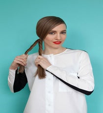 Once the ponytail is secure, create a rope braid. Divide the hair into two sections, twist them both in the same direction, and then cross the two sections over each other in the opposite direction. Here, Annie twisted both sections of hair toward her face, and then wrapped them away from her face. bun-4